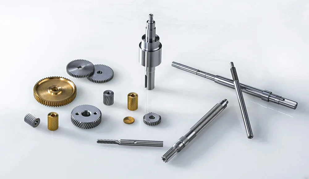 Turned shafts, gears and bushes laid out on a white surface
